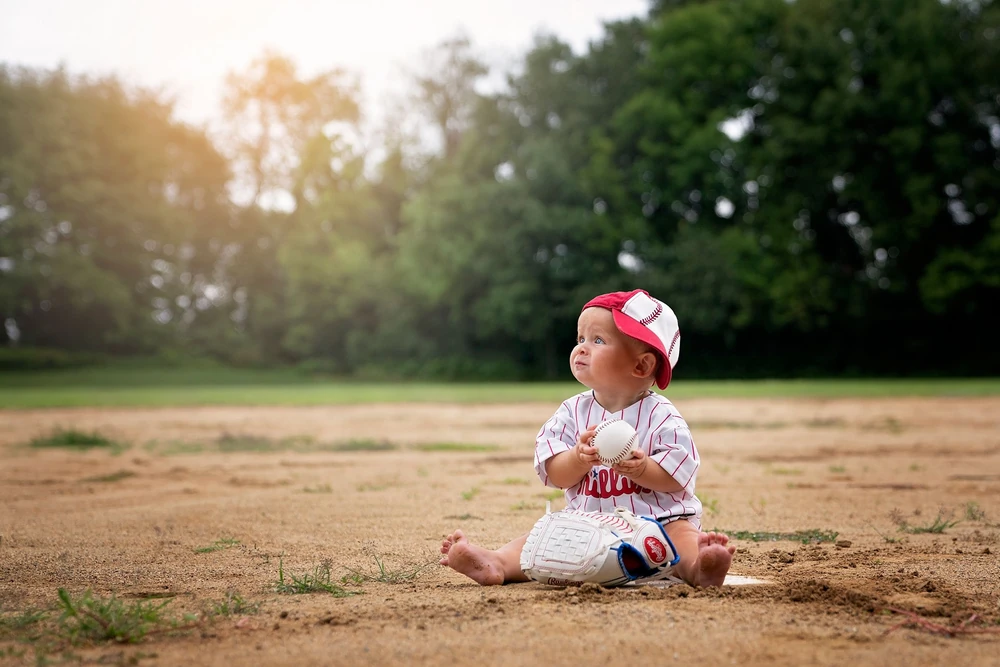 A baby sitting in the grass in warm evening light