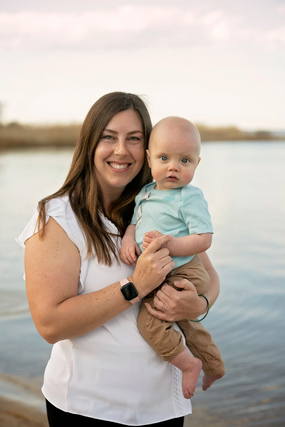 A mother holding her baby beside the water