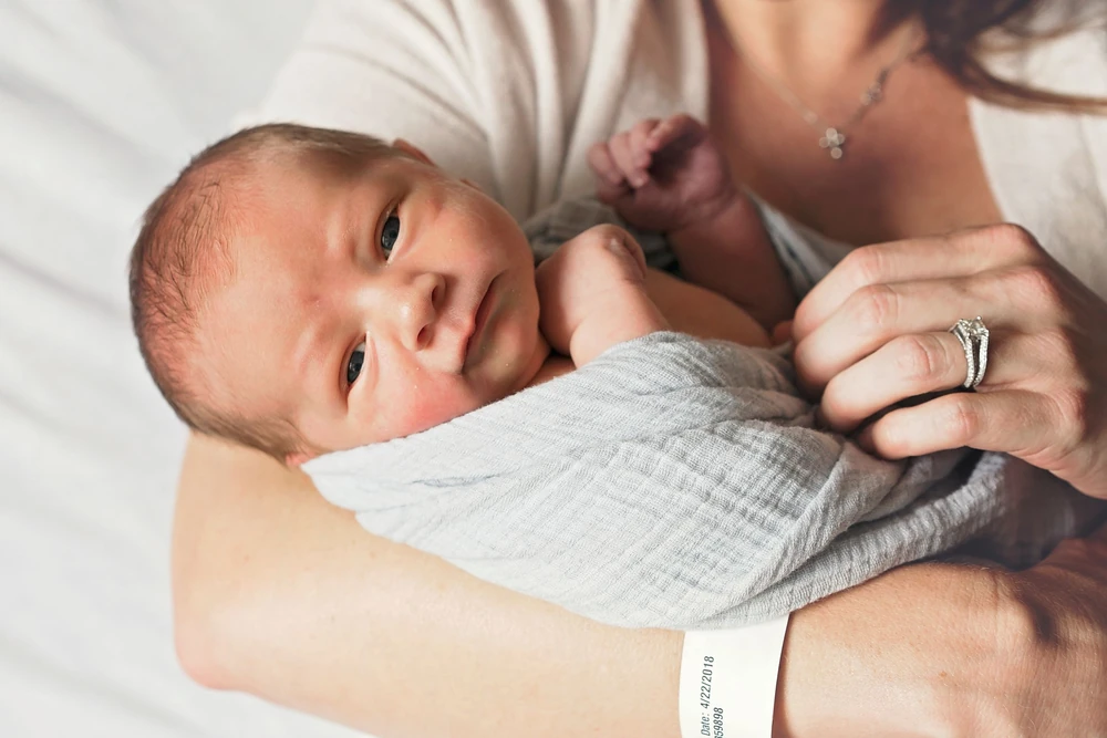 A newborn held close in a parent’s arms